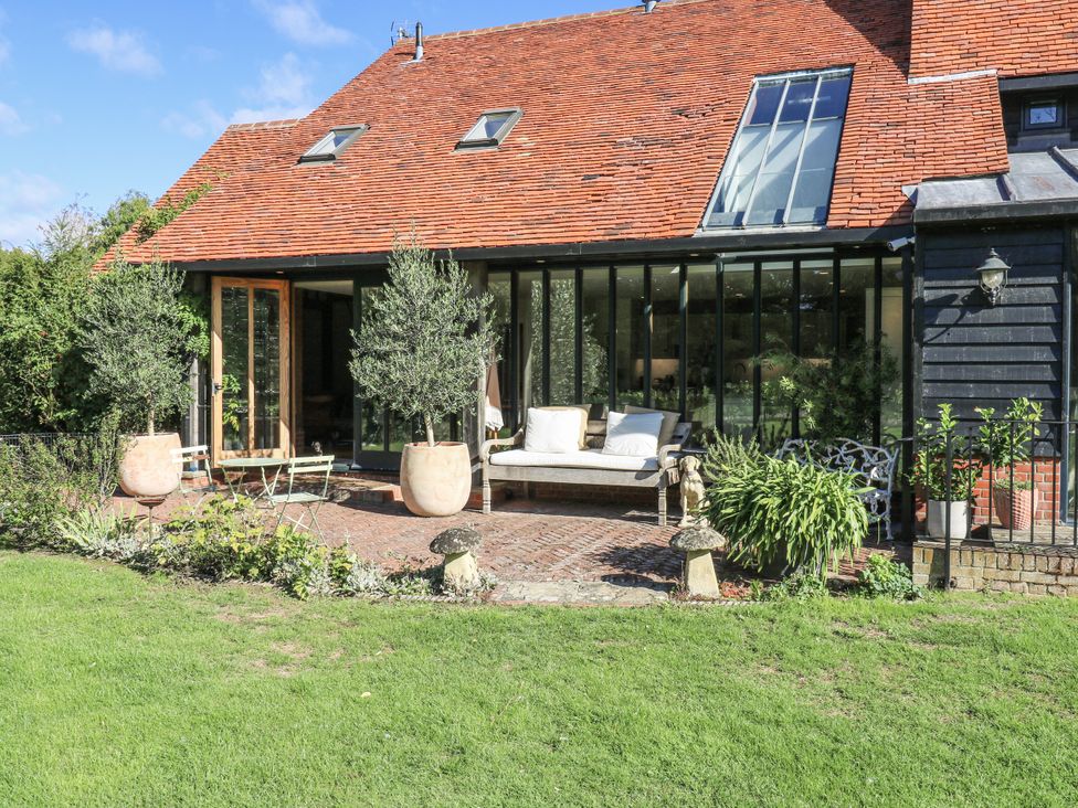 A garden area with a sofa and potted plants at Headland Barn in Maldon