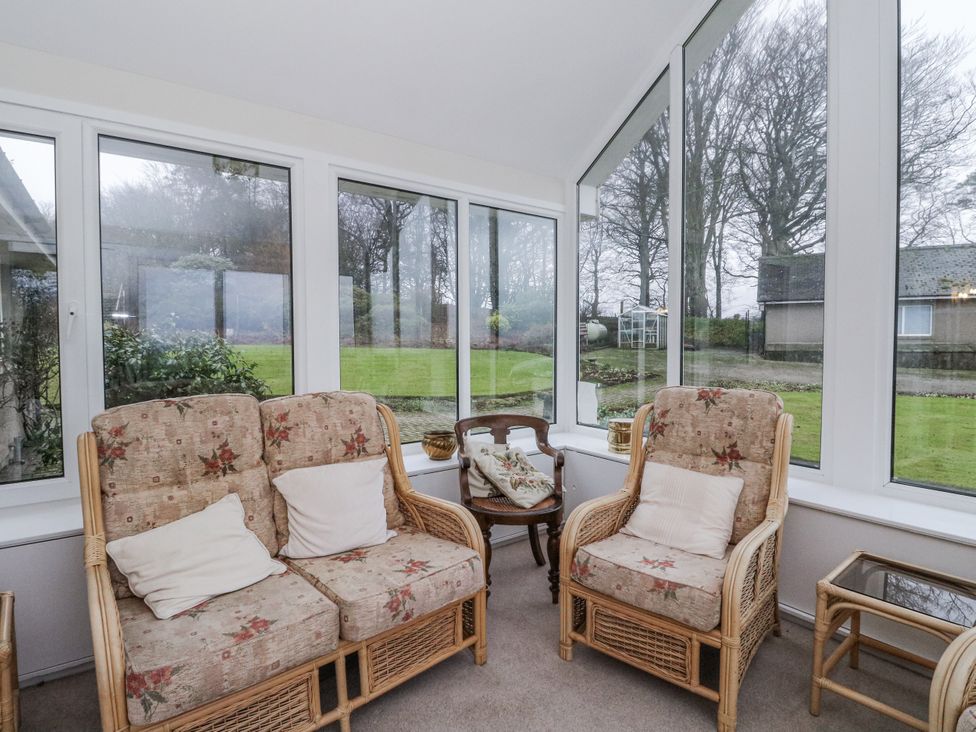 A conservatory with wicker chairs and glass table at Carnmhor in Aberdeen