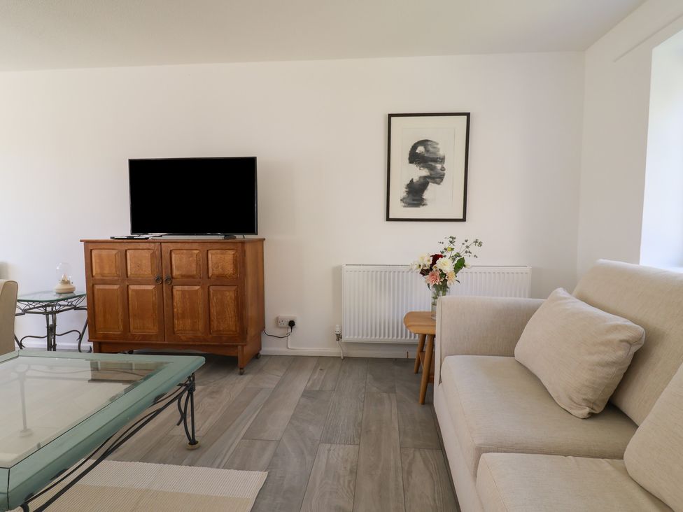 A living room with a television and a coffee table at Oakwood in Chideock