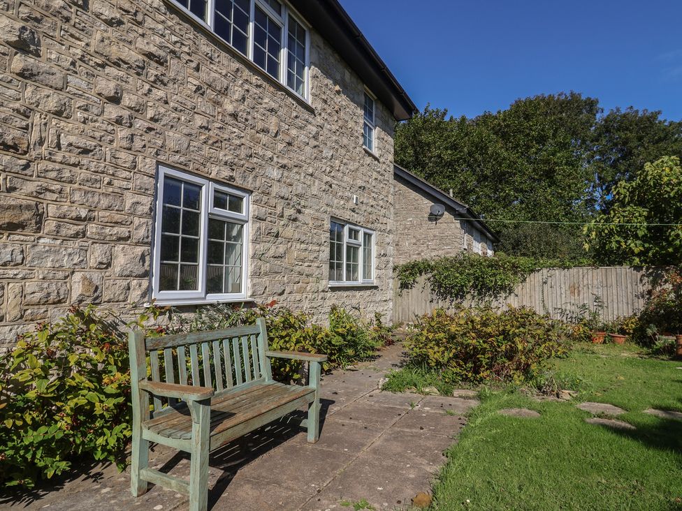 A garden with a stone wall and bench at Oakwood in Chideock