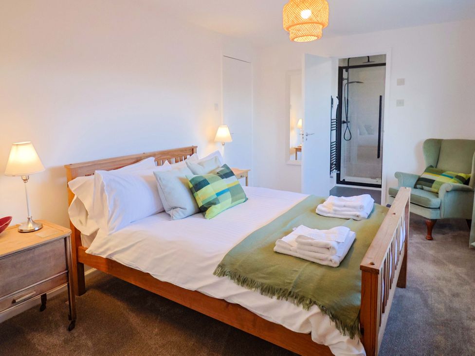 A bedroom with a bed and armchair at Oakwood in Chideock