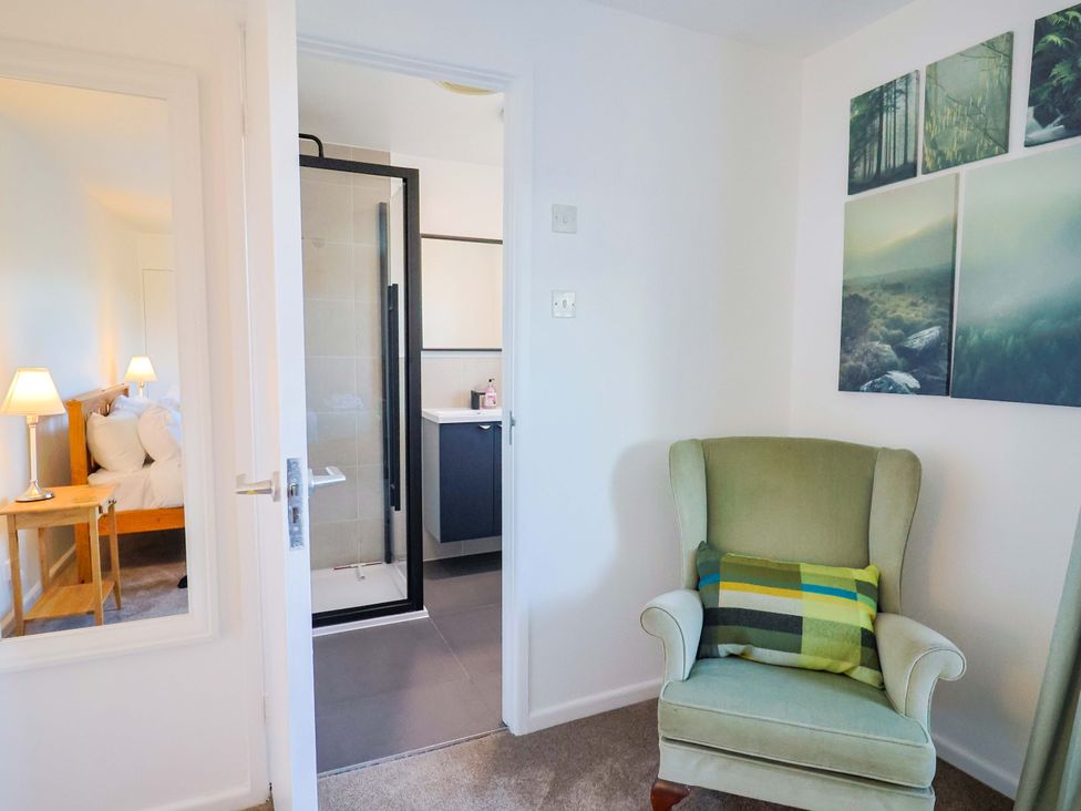 A bedroom with a bed, side table and bathroom entrance at Oakwood in Chideock