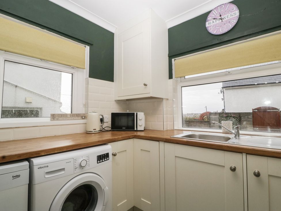 A laundry room with a washing machine and microwave at Gavin and Stacey House in Barry