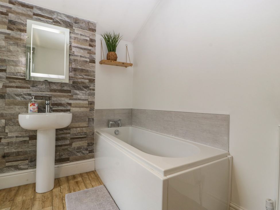 A bathroom with a sink, bathtub and a mirror at Gavin and Stacey House in Barry