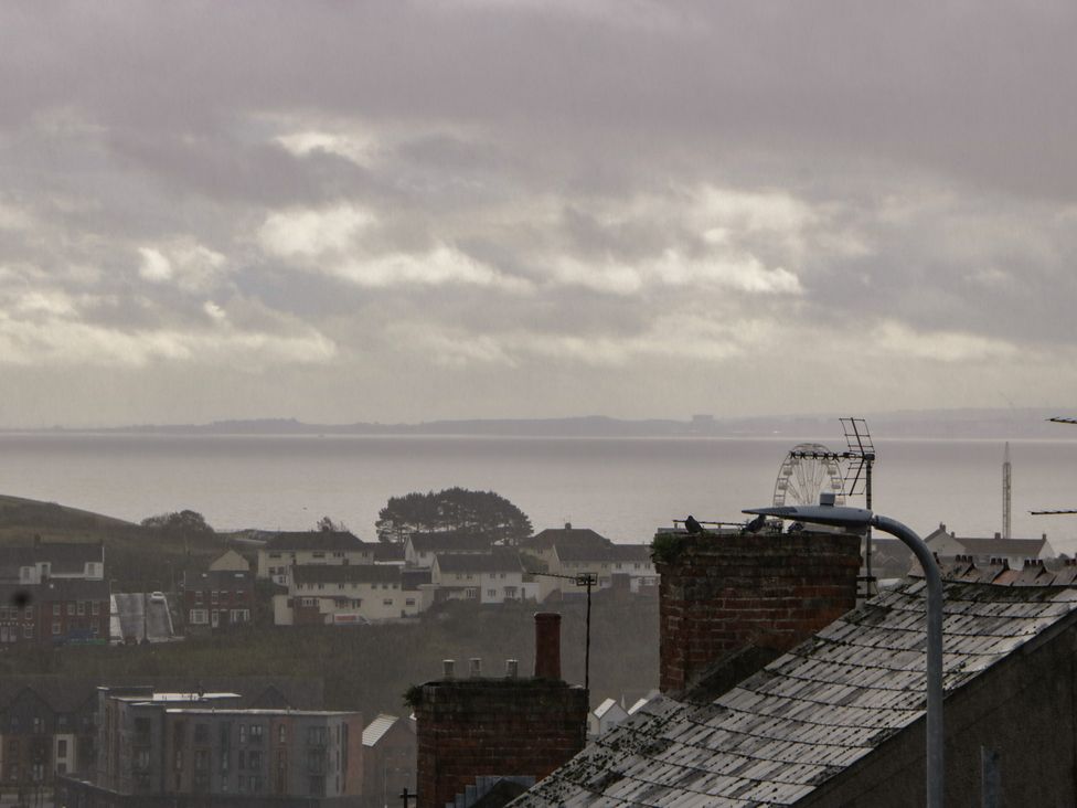 A view of the sea and buildings with a ferris wheel at Gavin and Stacey House in Barry