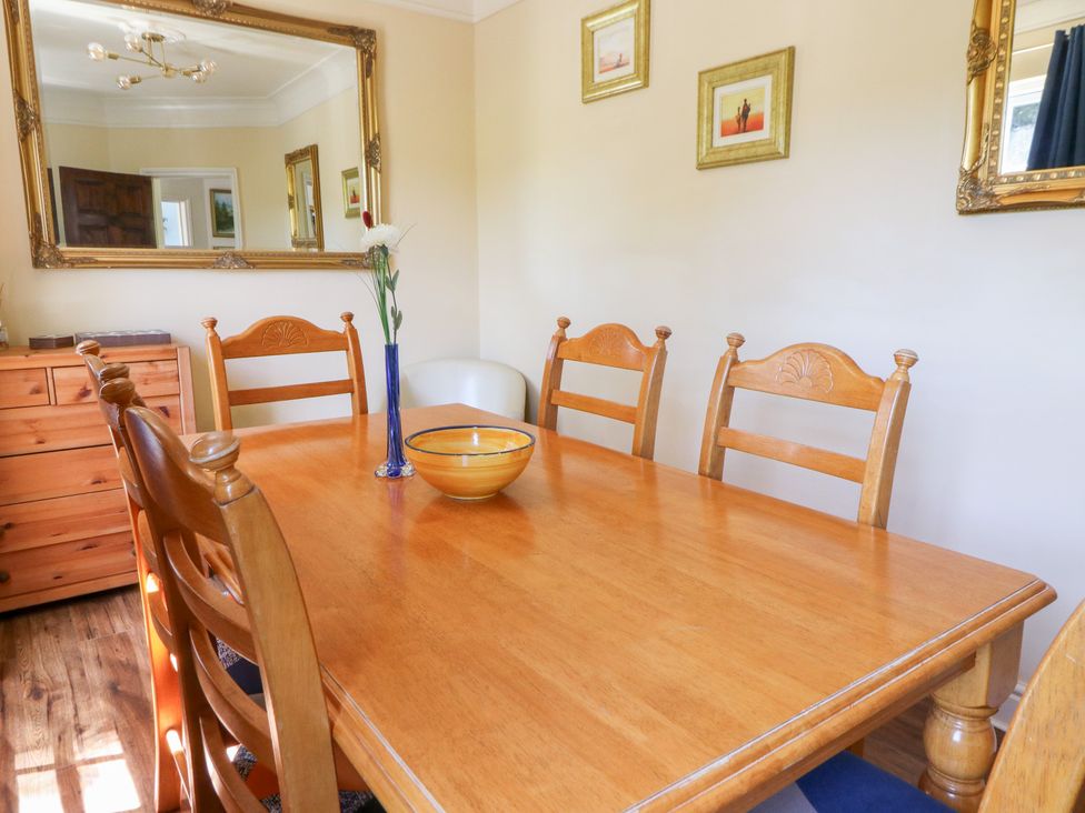 A dining room with a wooden table and chairs at Ty Caredig in Swansea