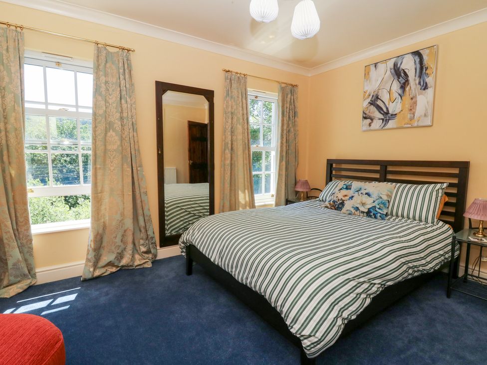 A bedroom with a bed and mirror at Ty Caredig in Swansea