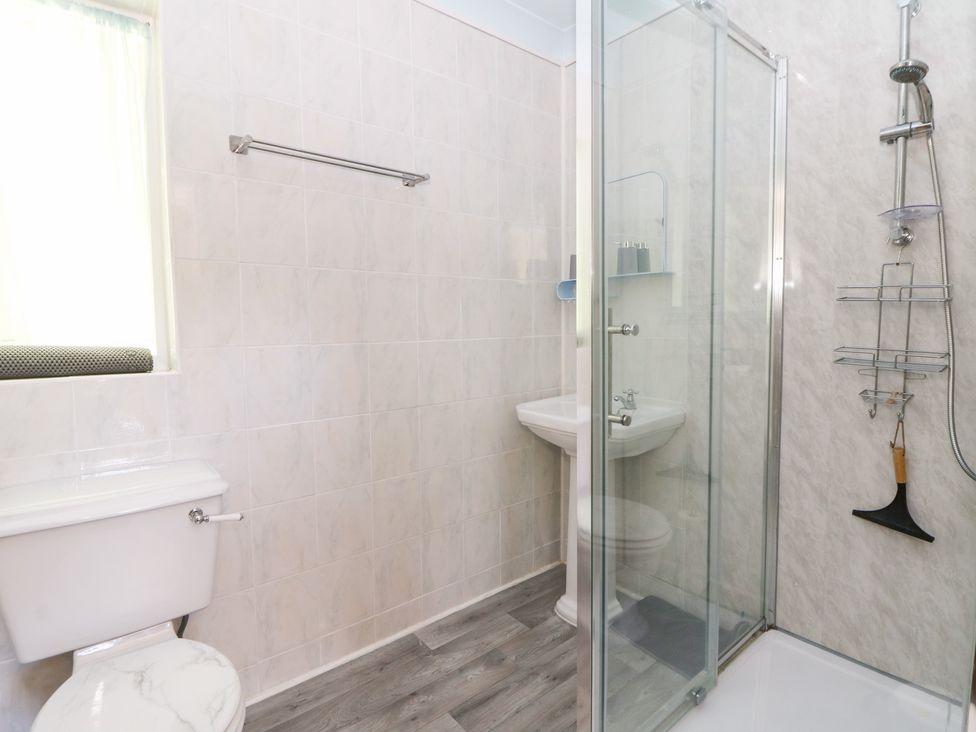 A bathroom with a toilet, sink, and shower at Ty Caredig in Swansea