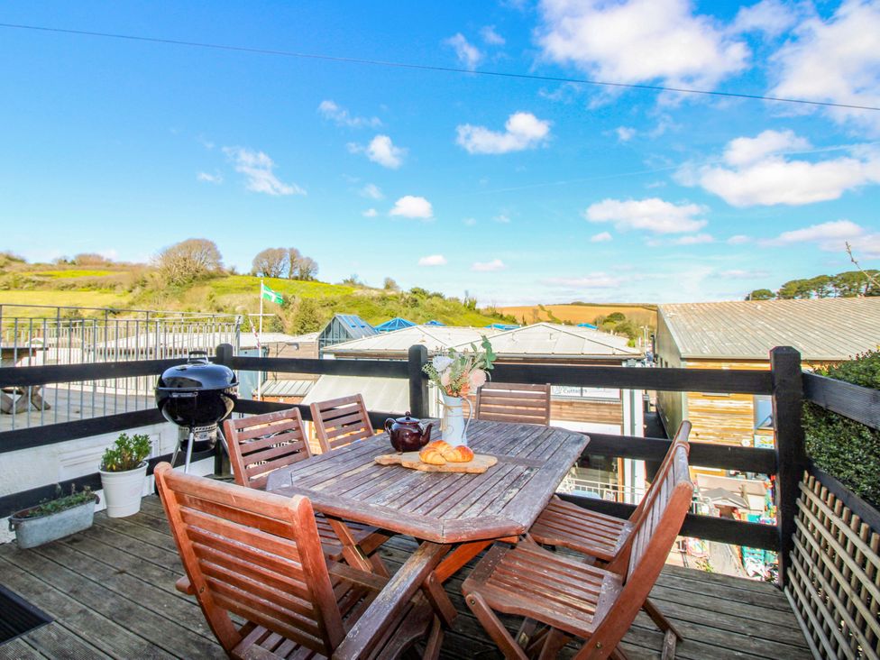 An outdoor patio with a wooden table and chairs at Rockside in Salcombe