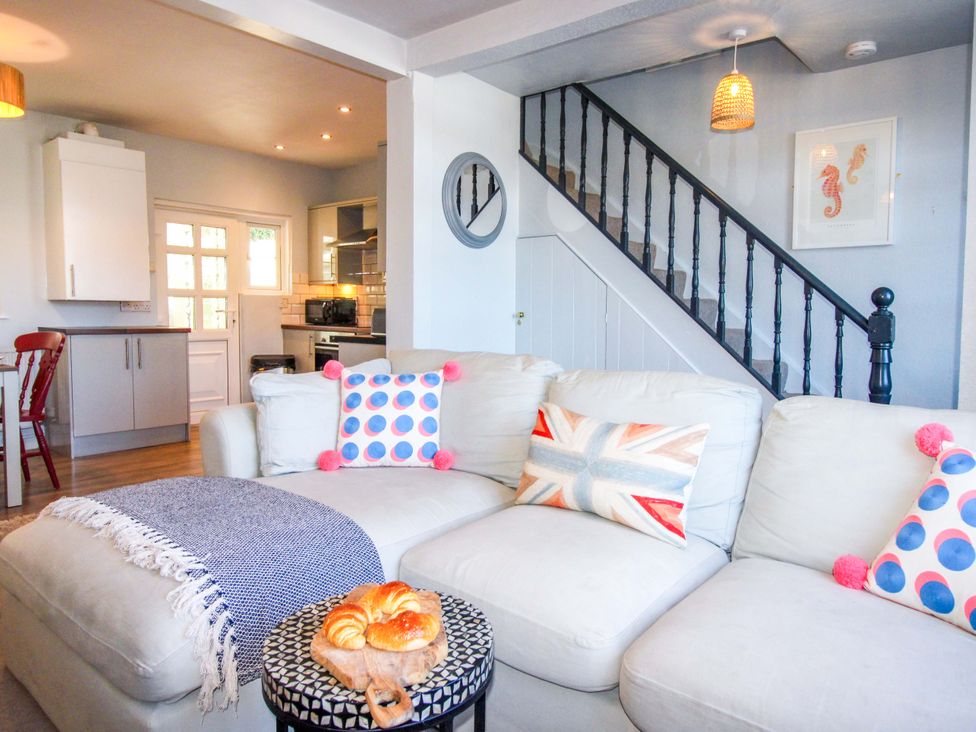A living room with a sofa and kitchen view at Rockside in Salcombe