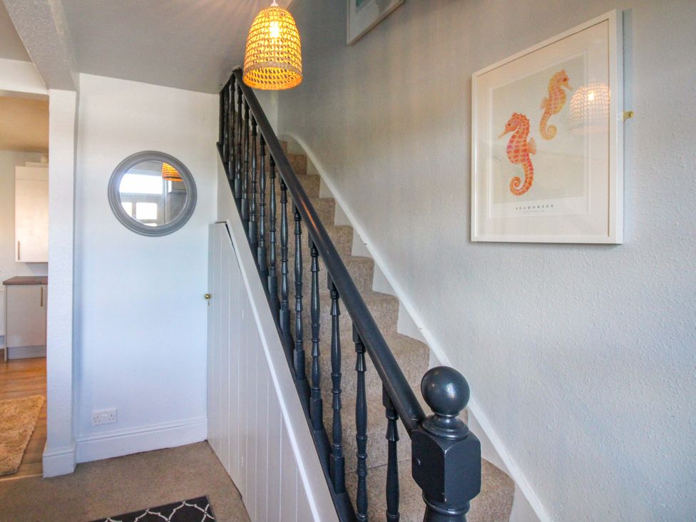 A hallway with a staircase and framed artwork at Rockside in Salcombe