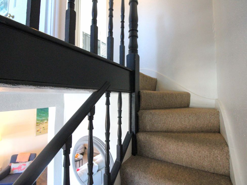 A staircase with a black banister at Rockside in Salcombe
