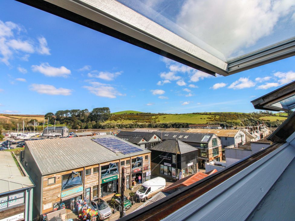 A view from a window overlooking buildings and hills at Rockside in Salcombe