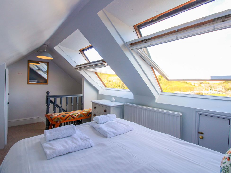 A bedroom with a bed and windows at Rockside in Salcombe