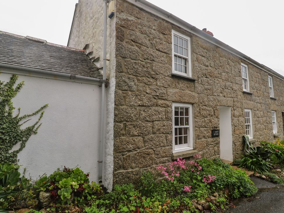 An exterior view of a stone cottage with a garden at 1 Rowes Cottages in Penzance