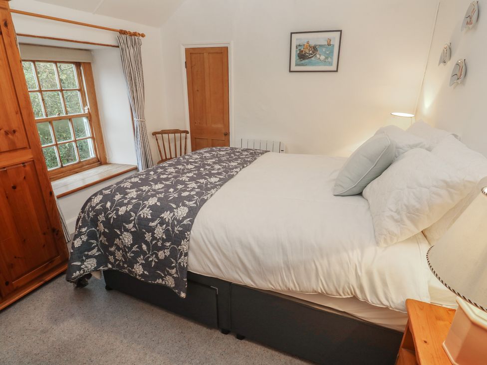 A bedroom with a bed and window at 1 Rowes Cottages in Penzance