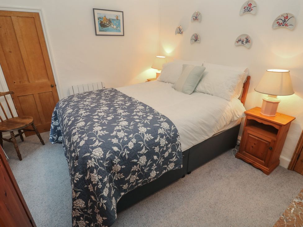 A bedroom with a bed and a chair at 1 Rowes Cottages in Penzance