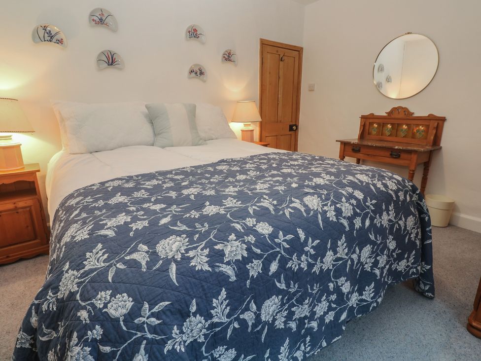 A bedroom with a bed and a desk at 1 Rowes Cottages in Penzance