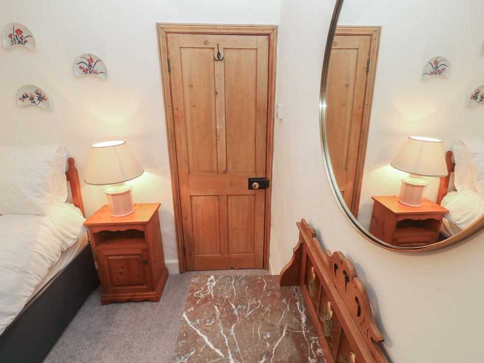 A bedroom with a bed and a lamp at 1 Rowes Cottages in Penzance