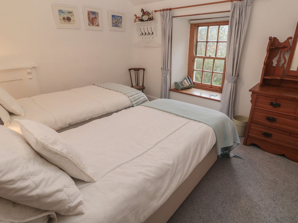 A bedroom with two beds and a window at 1 Rowes Cottages in Penzance