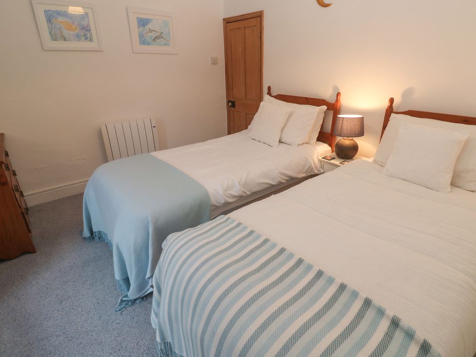 A bedroom with two beds and a lamp at 1 Rowes Cottages Penzance