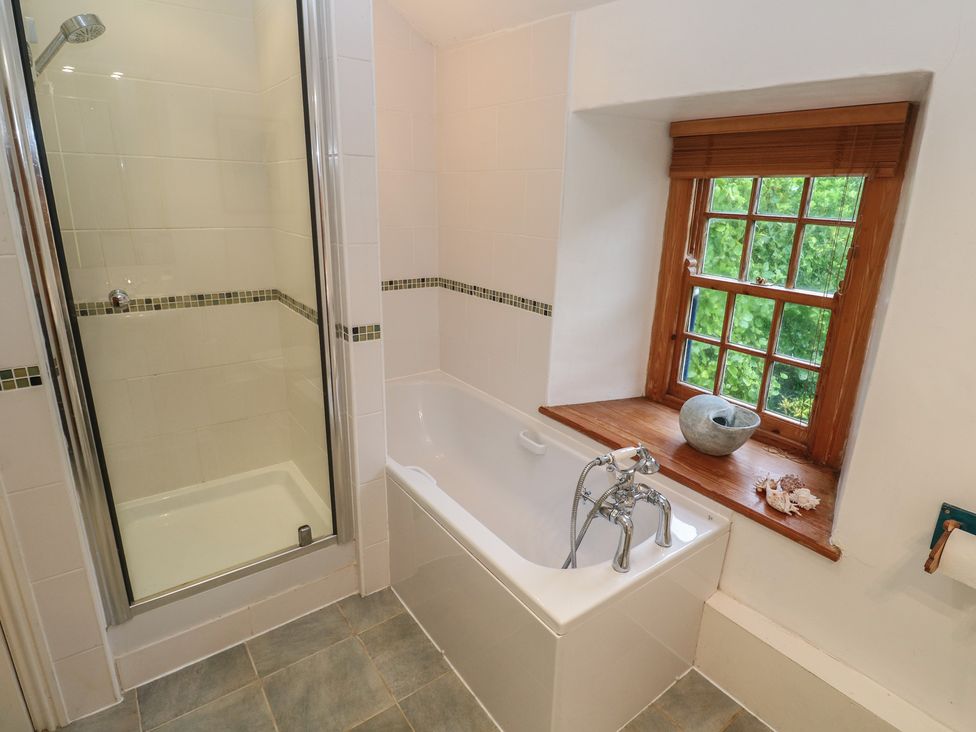 A bathroom with a shower and bathtub at 1 Rowes Cottages in Penzance
