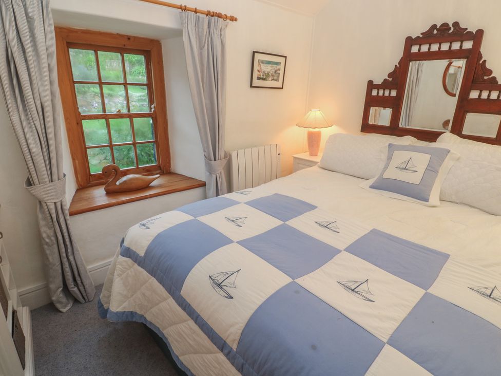 A bedroom with a bed and window at 1 Rowes Cottages in Penzance