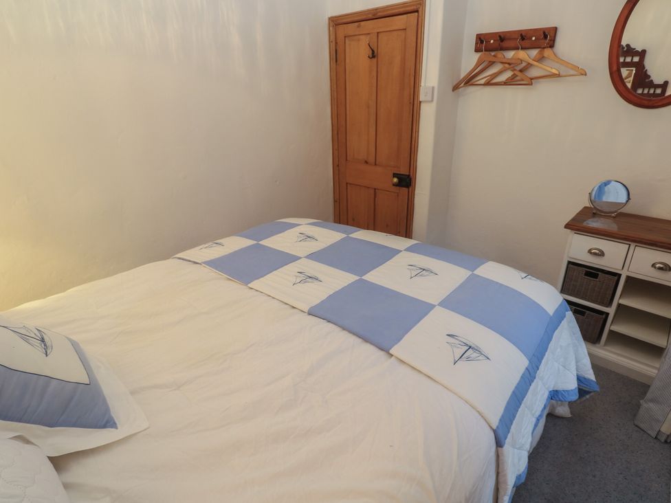 A bedroom with a bed and storage unit at 1 Rowes Cottages in Penzance