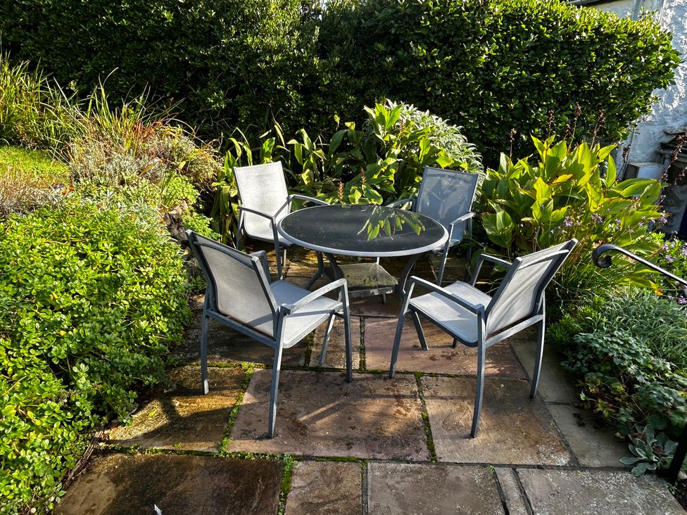 A table and chairs surrounded by plants at 1 Rowes Cottages in Porthgwarra