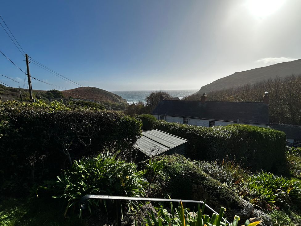 A view of the ocean and hills from a garden at 1 Rowes Cottages Porthgwarra