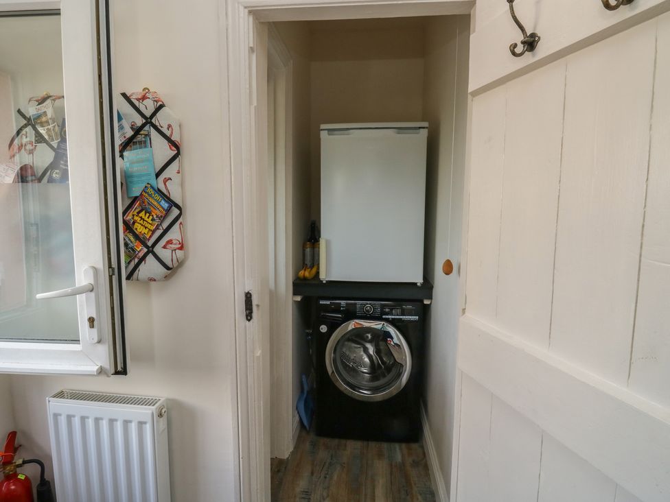A laundry room with a washing machine and fridge at 13 School Road in Newton Abbot