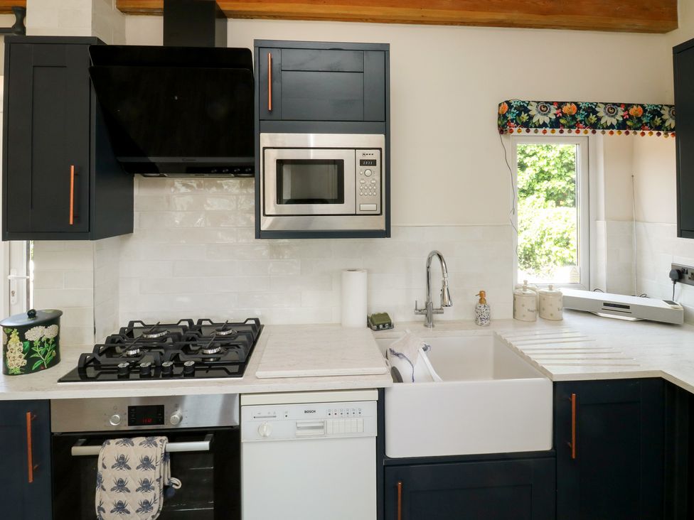 A kitchen with a gas stove, microwave, and sink at 13 School Road in Newton Abbot
