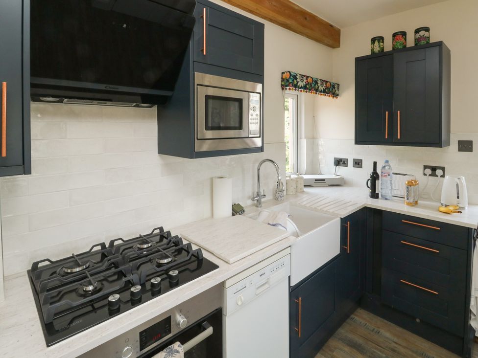 A kitchen with a sink, stove, and microwave at 13 School Road, Newton Abbot