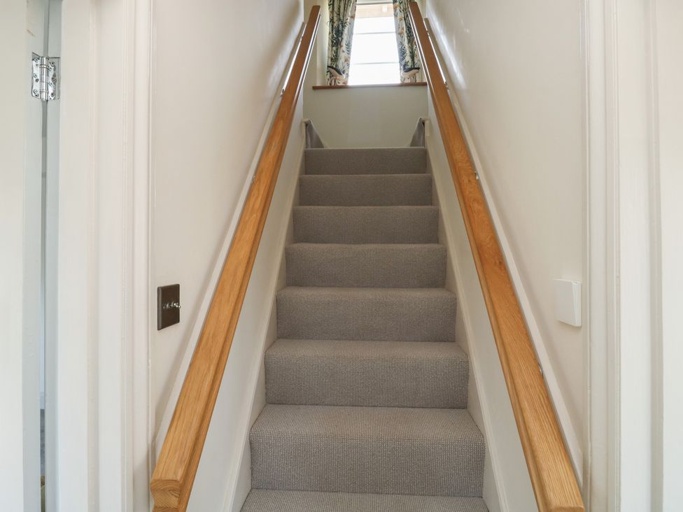 A staircase with a handrail and door at 13 School Road, Newton Abbot