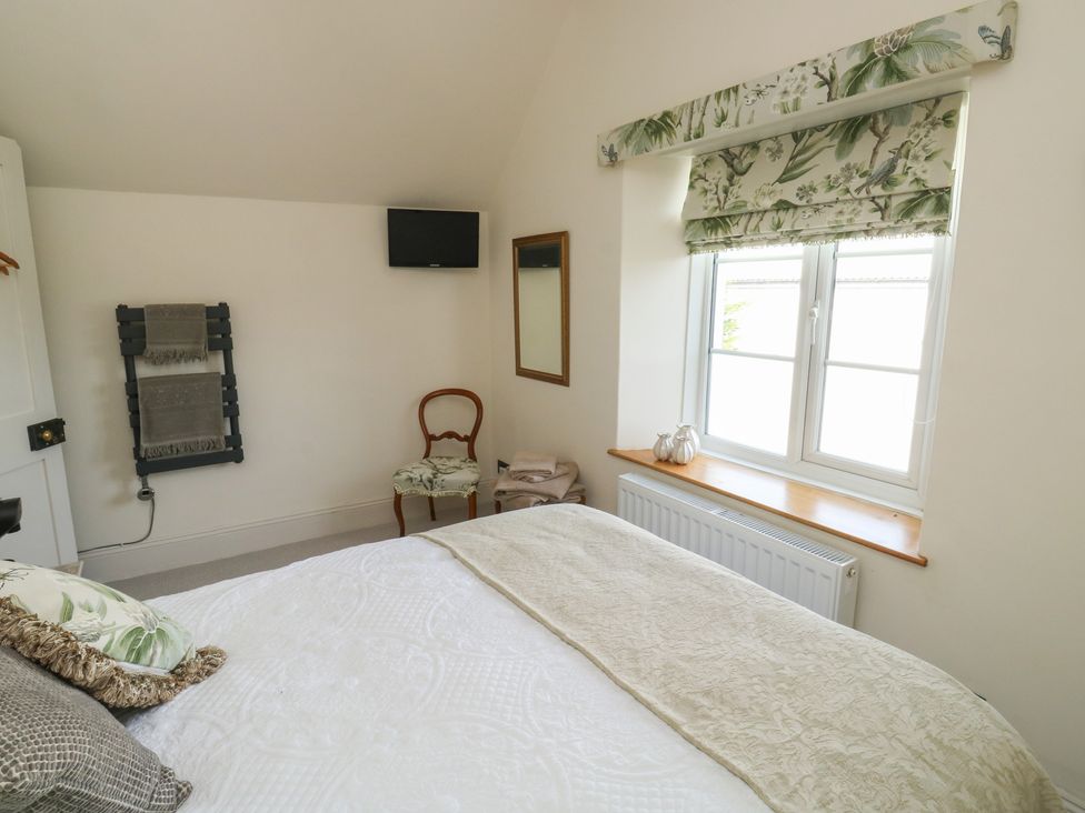 A bedroom with a bed, chair, mirror, and television at 13 School Road, Newton Abbot