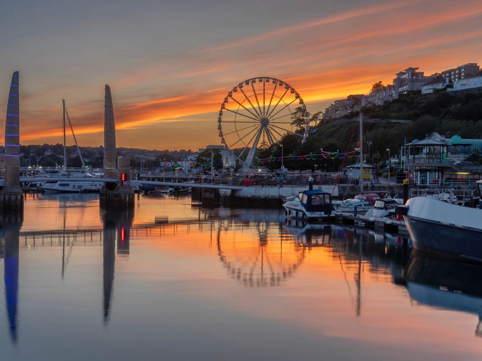 A harbor with boats and a ferris wheel at sunset at 13 School Road in Kingskerswell