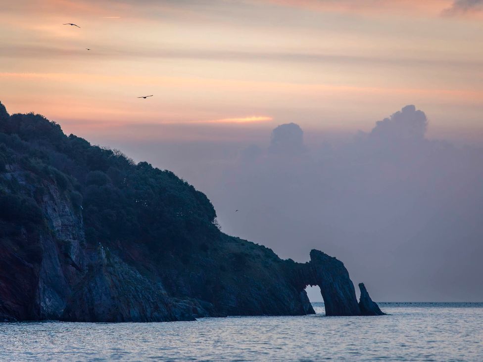 A cliff with a rock formation near the sea at 13 School Road Kingskerswell