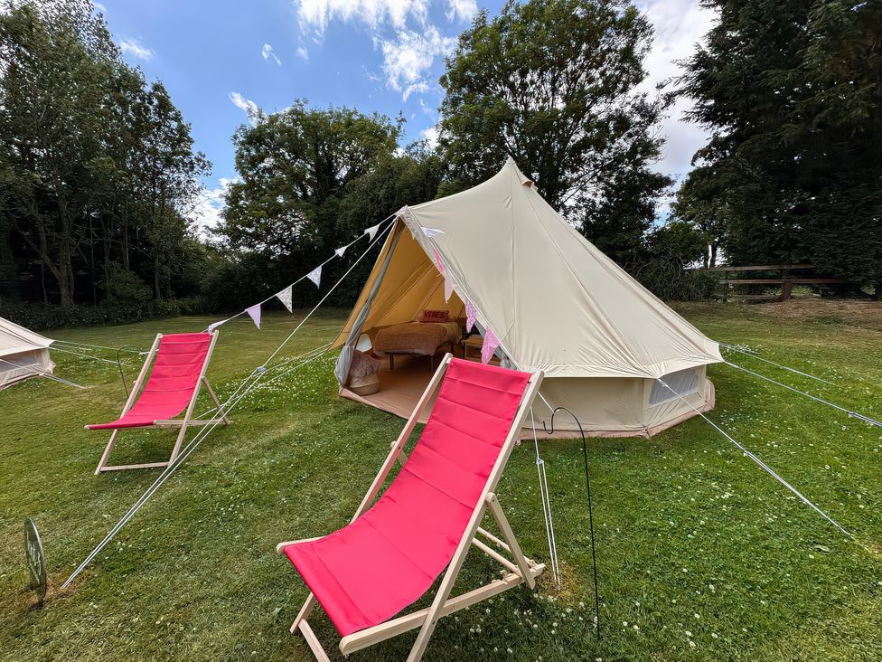 A tent with deck chairs on grass at Bell Tent