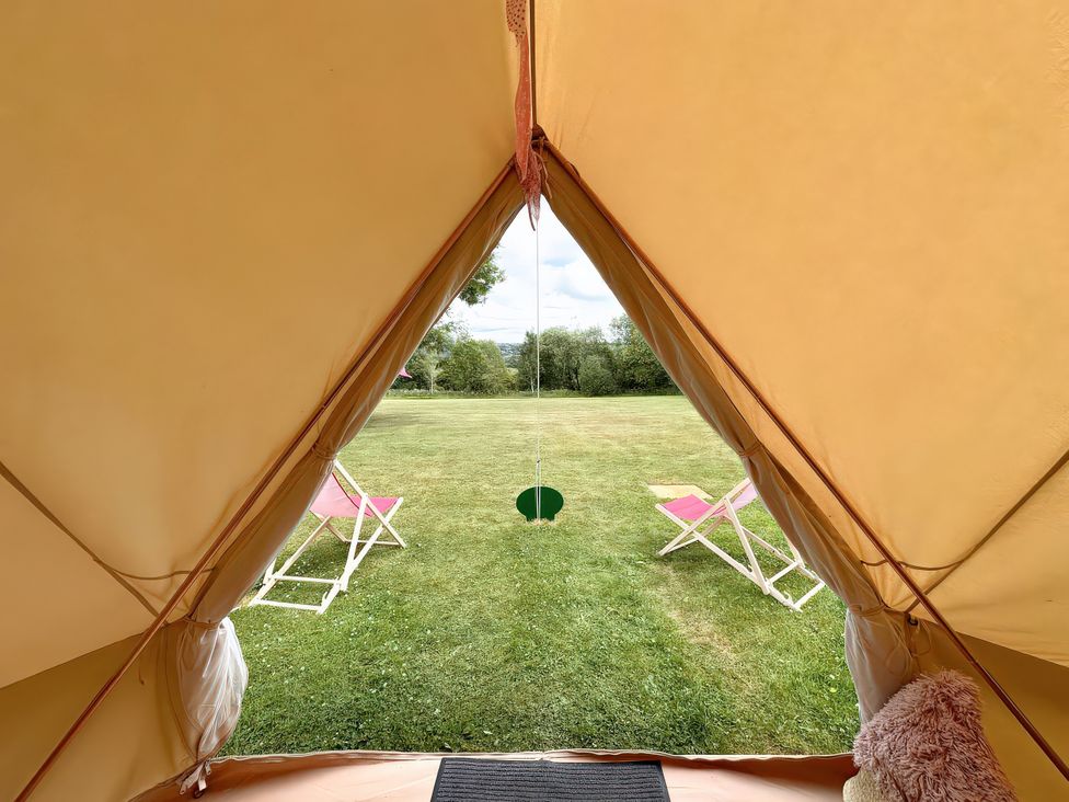 A view from inside a tent looking out onto grass and chairs at Bell Tent