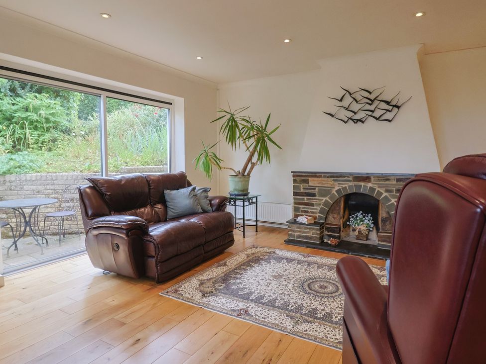 A living room with a sofa, armchair and fireplace at Hawksdown in Lyme Regis