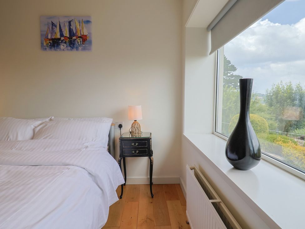 A bedroom with a bed, lamp, and vase at Hawksdown in Lyme Regis