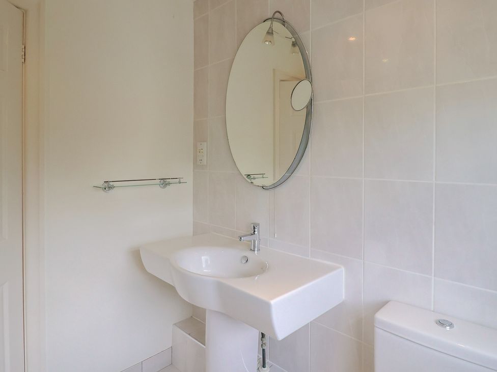 A bathroom with a sink, toilet, and mirror at Hawksdown Lyme Regis
