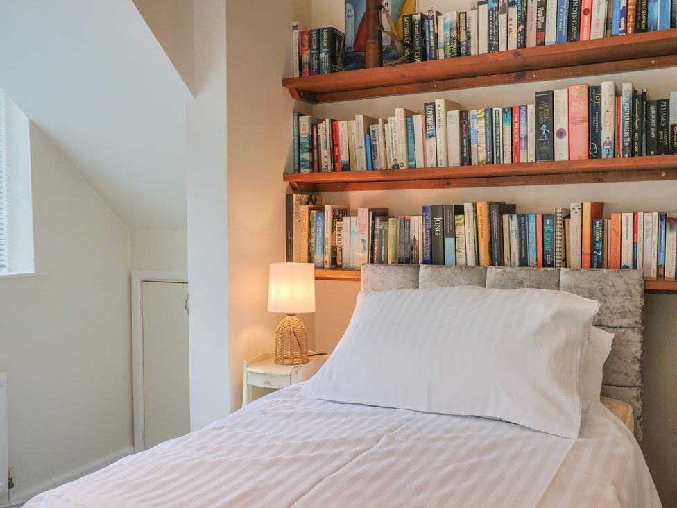 A bedroom with a bed, bookshelf, and lamp at Hawksdown in Lyme Regis