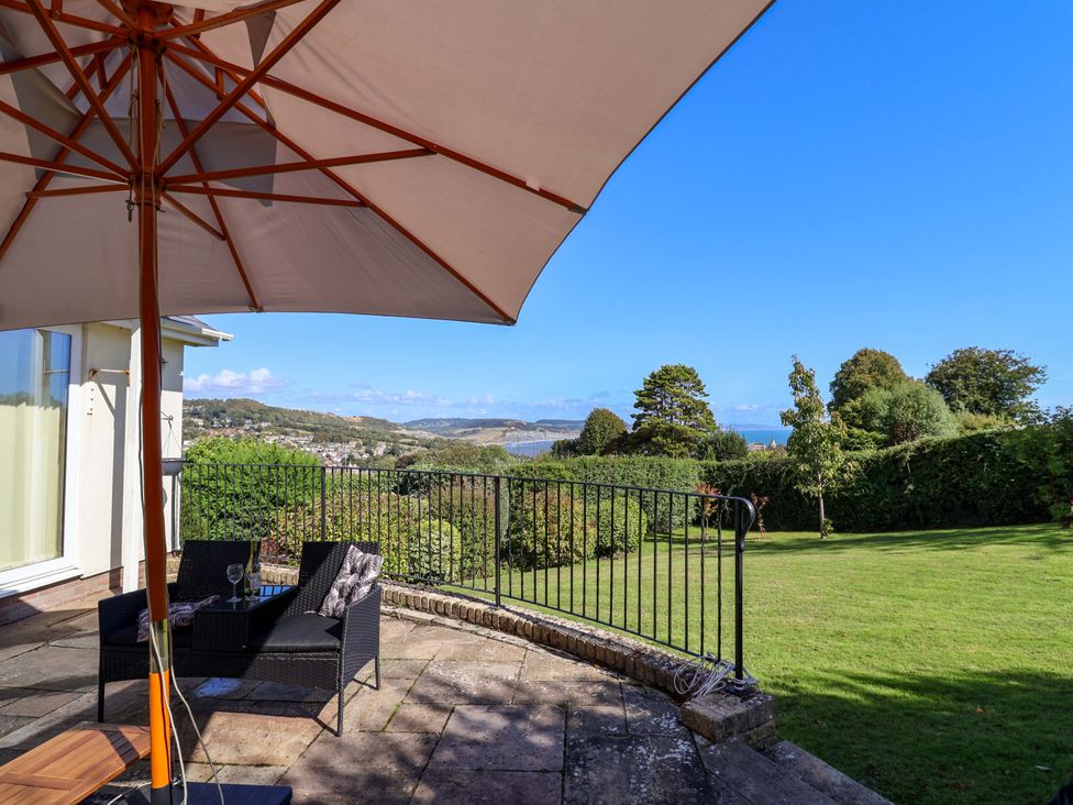 An outdoor area with chairs and table under an umbrella at Hawksdown Lyme Regis