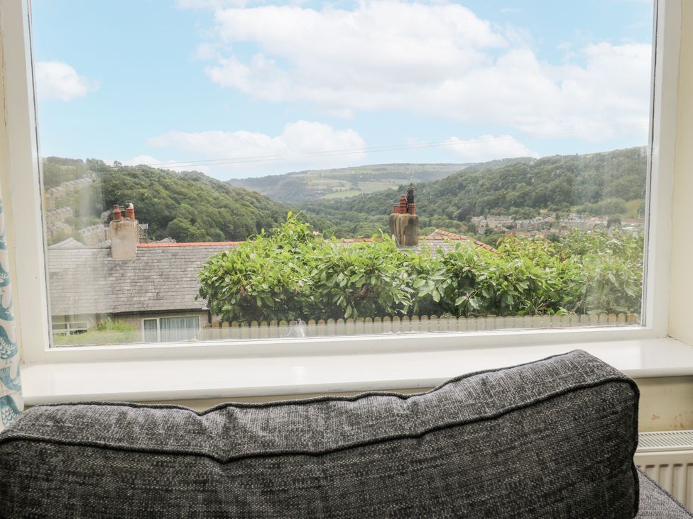 A view of mountains and houses from a window with a couch at The Vista in Hebden Bridge