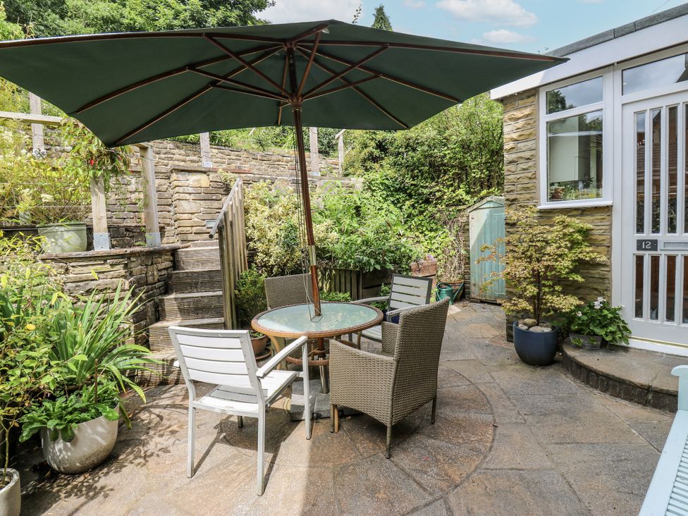 A garden with a table and chairs under an umbrella at The Vista in Hebden Bridge