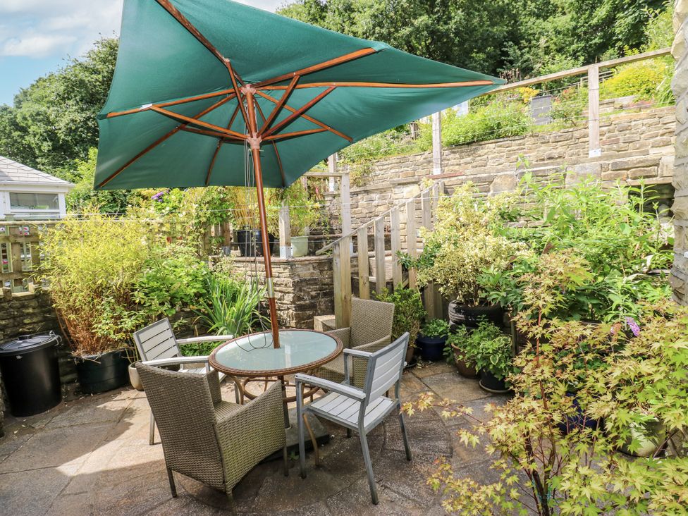 A garden with a table and chairs under an umbrella at The Vista in Hebden Bridge