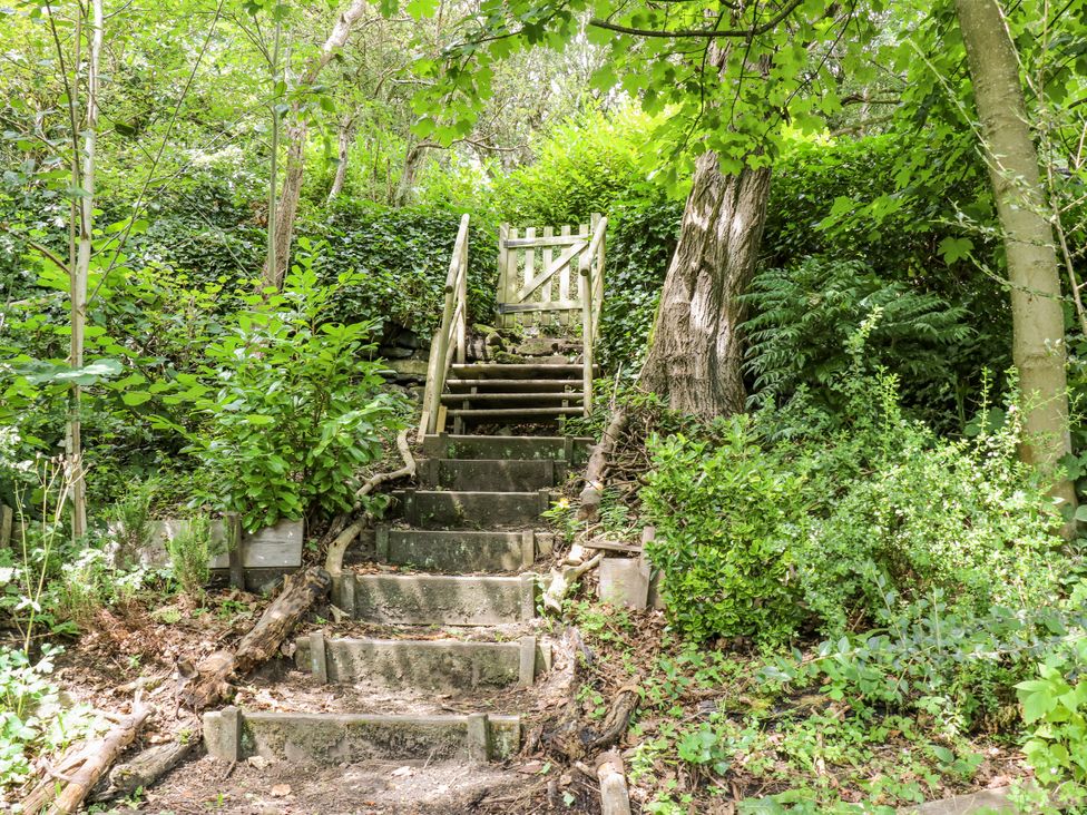 Steps leading to a gate surrounded by trees and plants at The Vista in Hebden Bridge