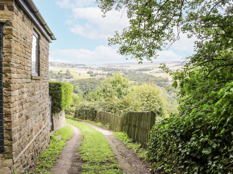 A path leading downhill with trees and a fence at The Vista in Hebden Bridge