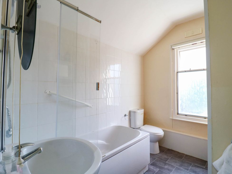 A bathroom with a shower, bathtub, toilet and window at Dover Retreat